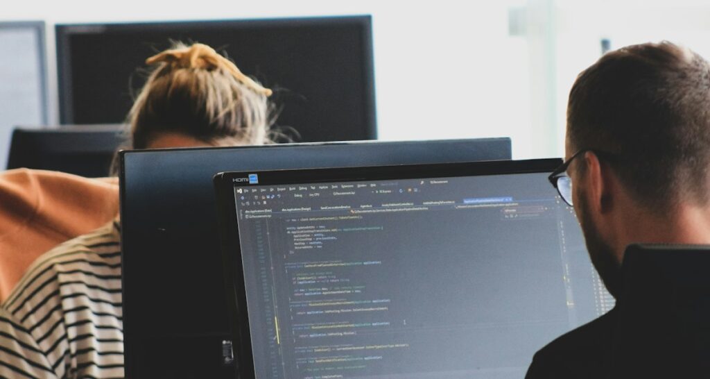 Zwei Personen entwickeln gemeinsam am Computer eine Low-Code-Anwendung für die Fertigung